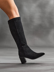 Model wearing Levine black faux suede block heel long boots